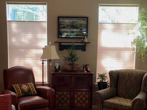 A cozy living room interior with two leather chairs back by tall windows